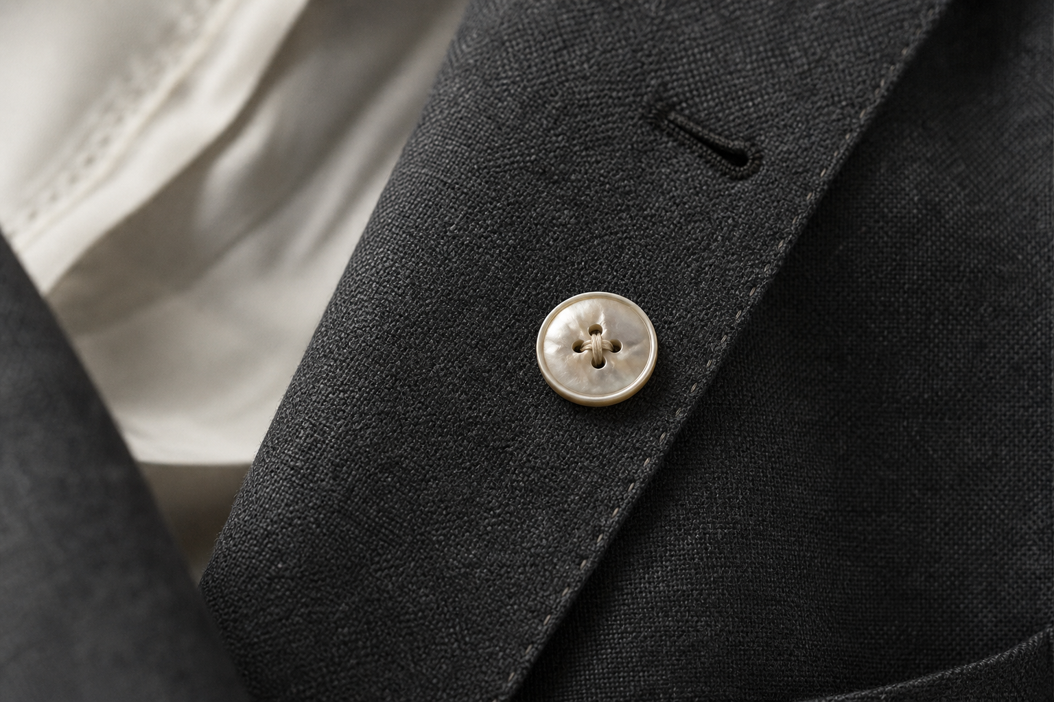 Detalle de blazer charcoal — botón nácar, costura a mano